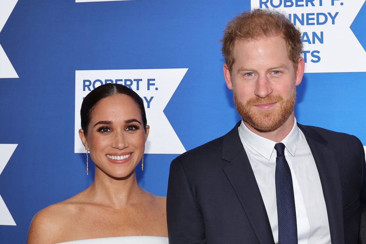 Meghan Markle and Prince Harry, whose Sussex website rebrand has reportedly not gone over 'well' with Buckingham Palace, smile and look on