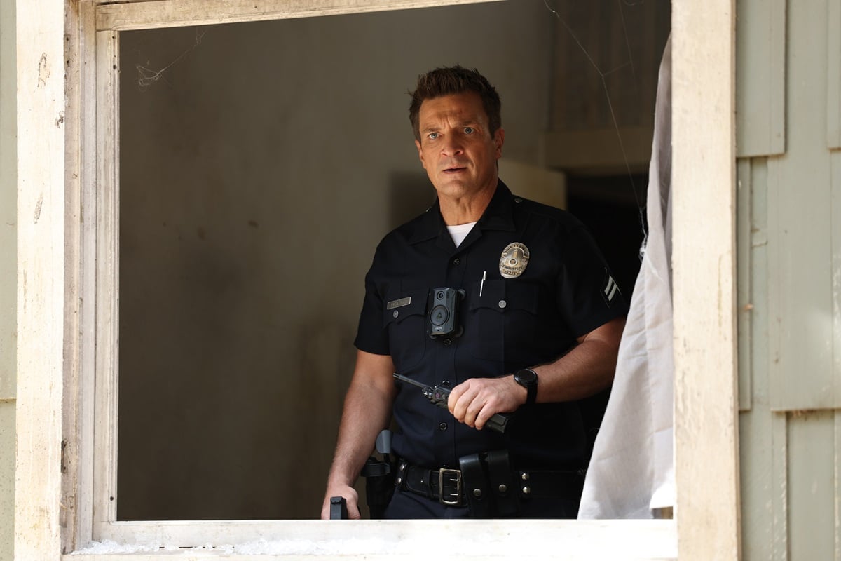 Nathan Fillion staring out the window while wearing a police uniform in an episode of 'The Rookie'.