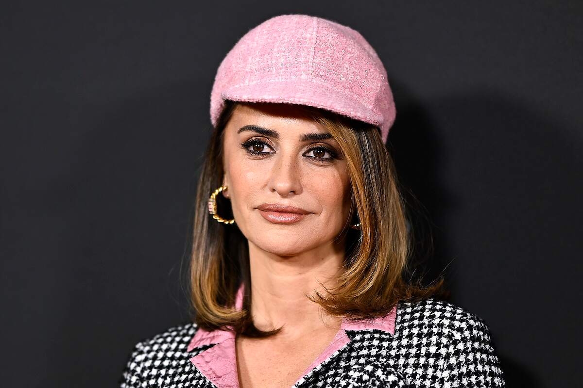 Actress Penelope Cruz looks at cameras while wearing a pink hat and tweed blazer