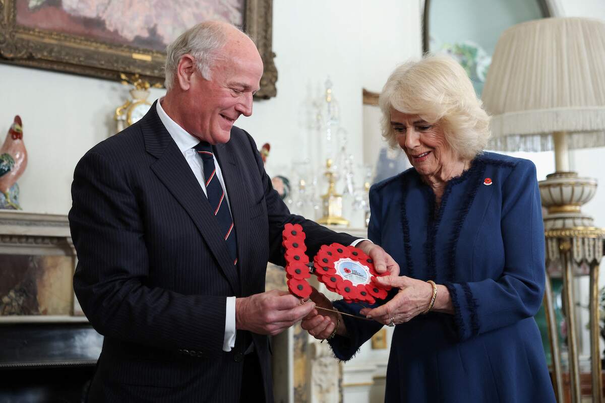 President of The Poppy Factory Surgeon Rear Admiral Lionel Jarvis hands a gift to Queen Camilla during a reception at Clarence House