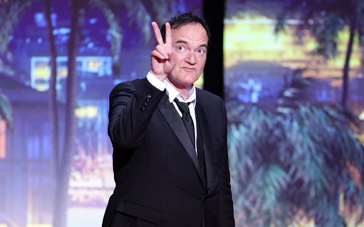 Quentin Tarantino posing on stage throwing the peace sign at the 76th annual Cannes film festival.