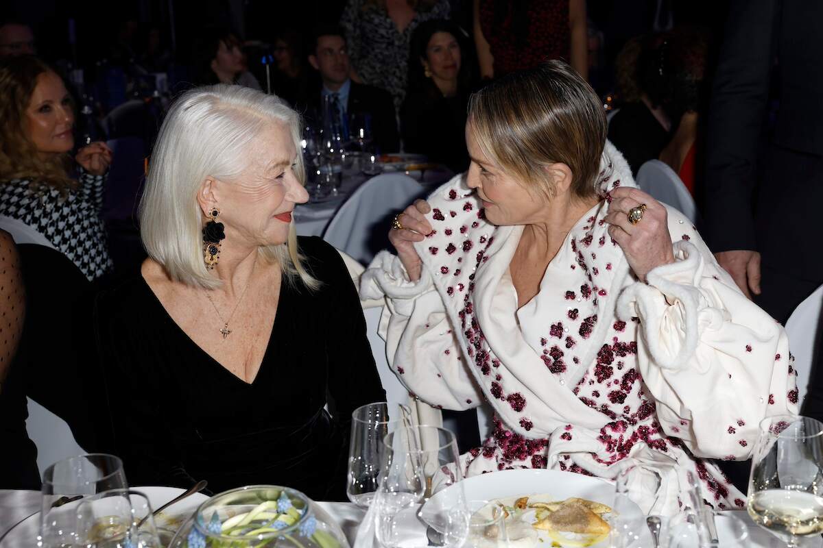 Helen Mirren and Sharon Stone smile at each other while eating dinner at the Cinema For Peace Gala