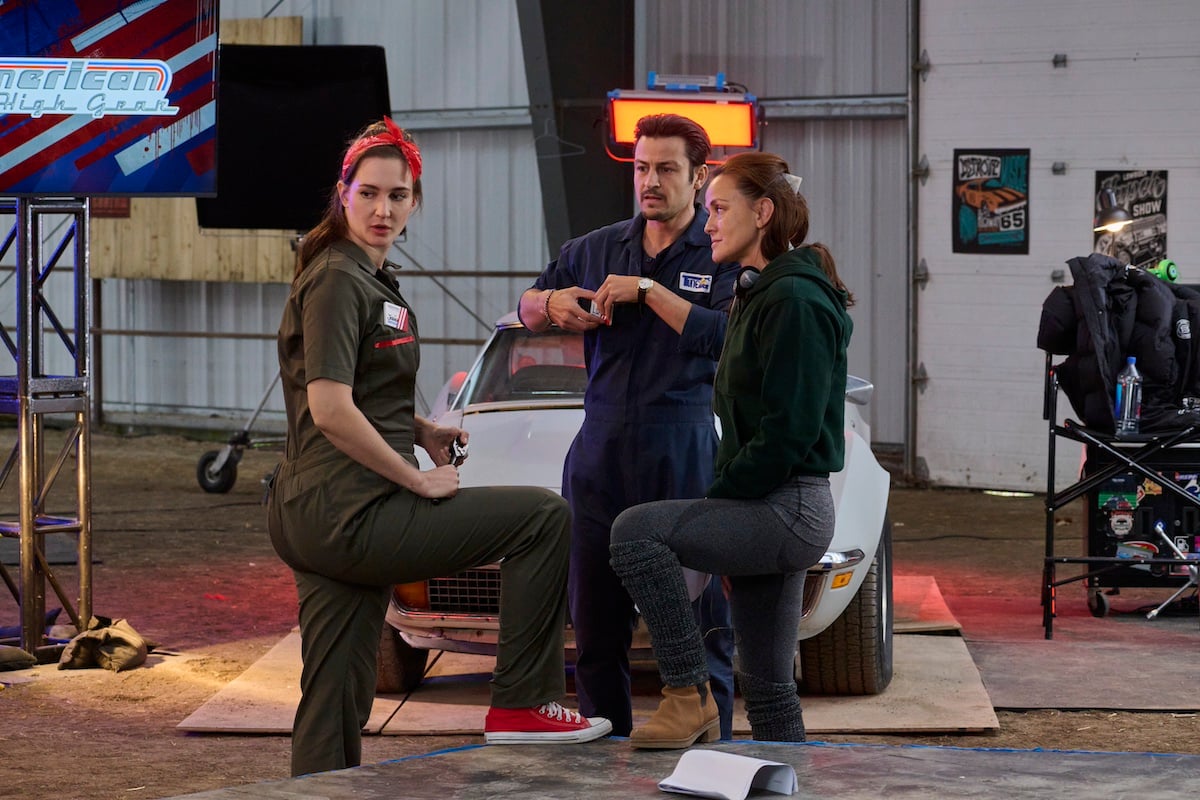 Katherin Barrell, Tyler Hynes, and Yan-Kay Crystal Lowe standing in front of a white car on the set of 'Shifting Gears'