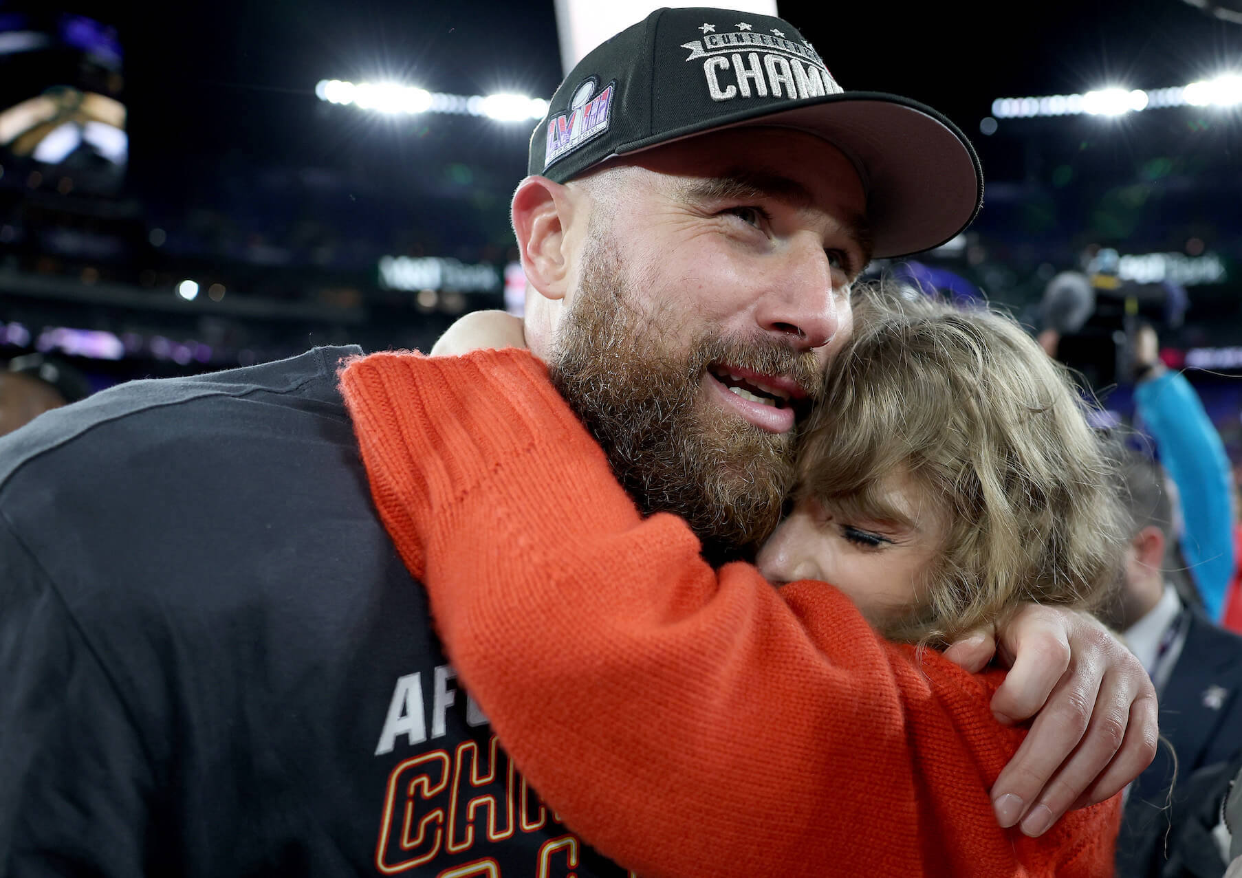 Travis Kelce smiling while embracing Taylor Swift after a Kansas City Chiefs game