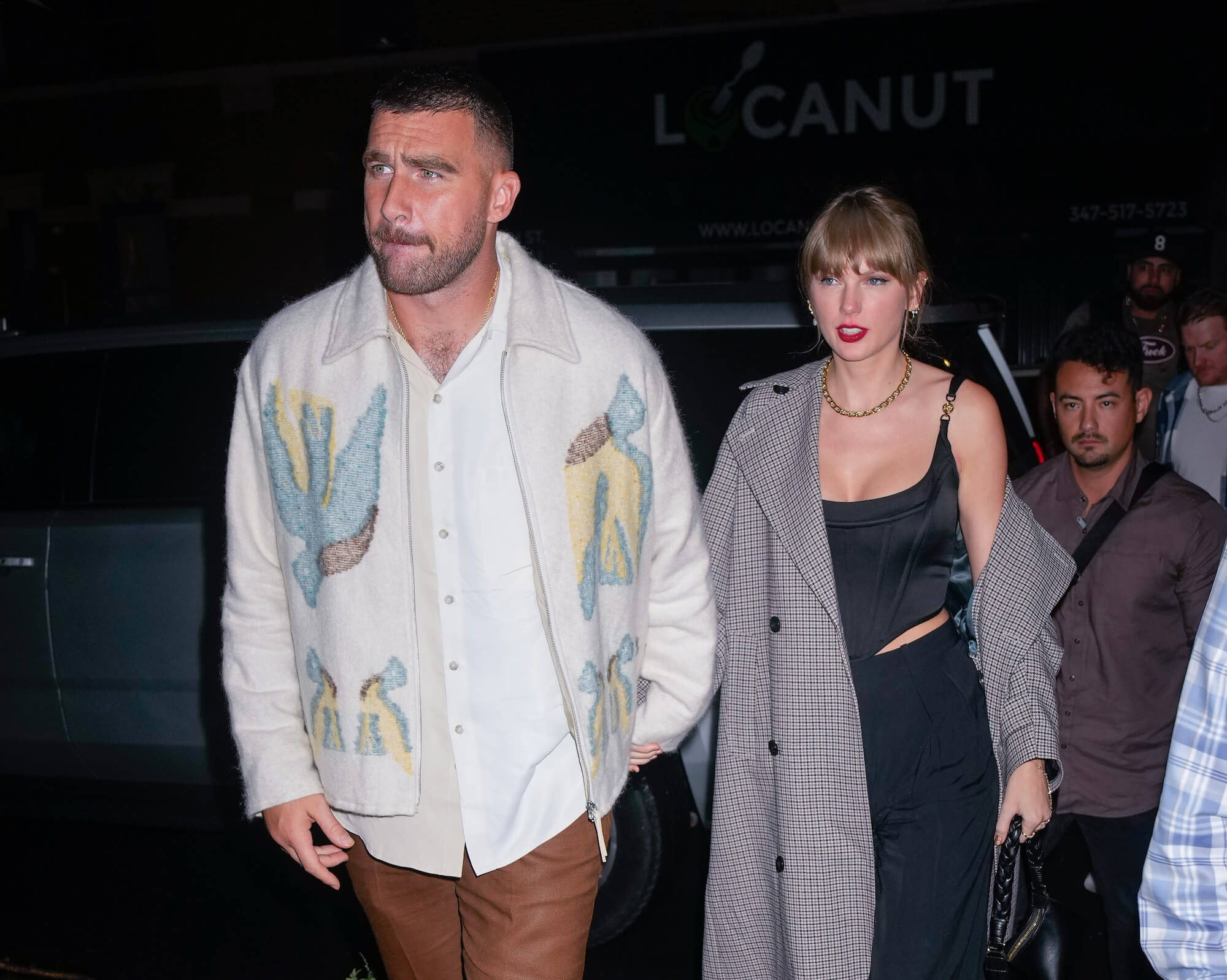 Travis Kelce and Taylor Swift walking hand in hand at night after a party