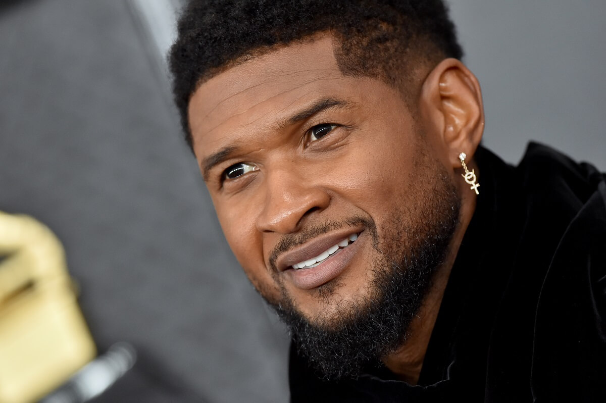 Usher smiling while at the 62nd Annual GRAMMY Awards wearing a black outfit.