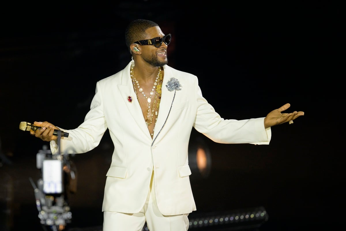 Usher performing onstage during his residency at La Seine Musicale while wearing a white suit.