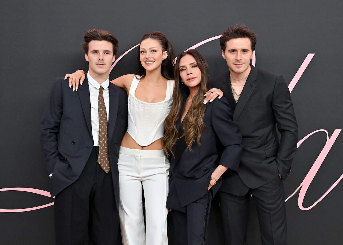 Cruz Beckham, Nicola Peltz Beckham, Victoria Beckham and Brooklyn Peltz Beckham smile together at the premier of a movie wearing all black and all white