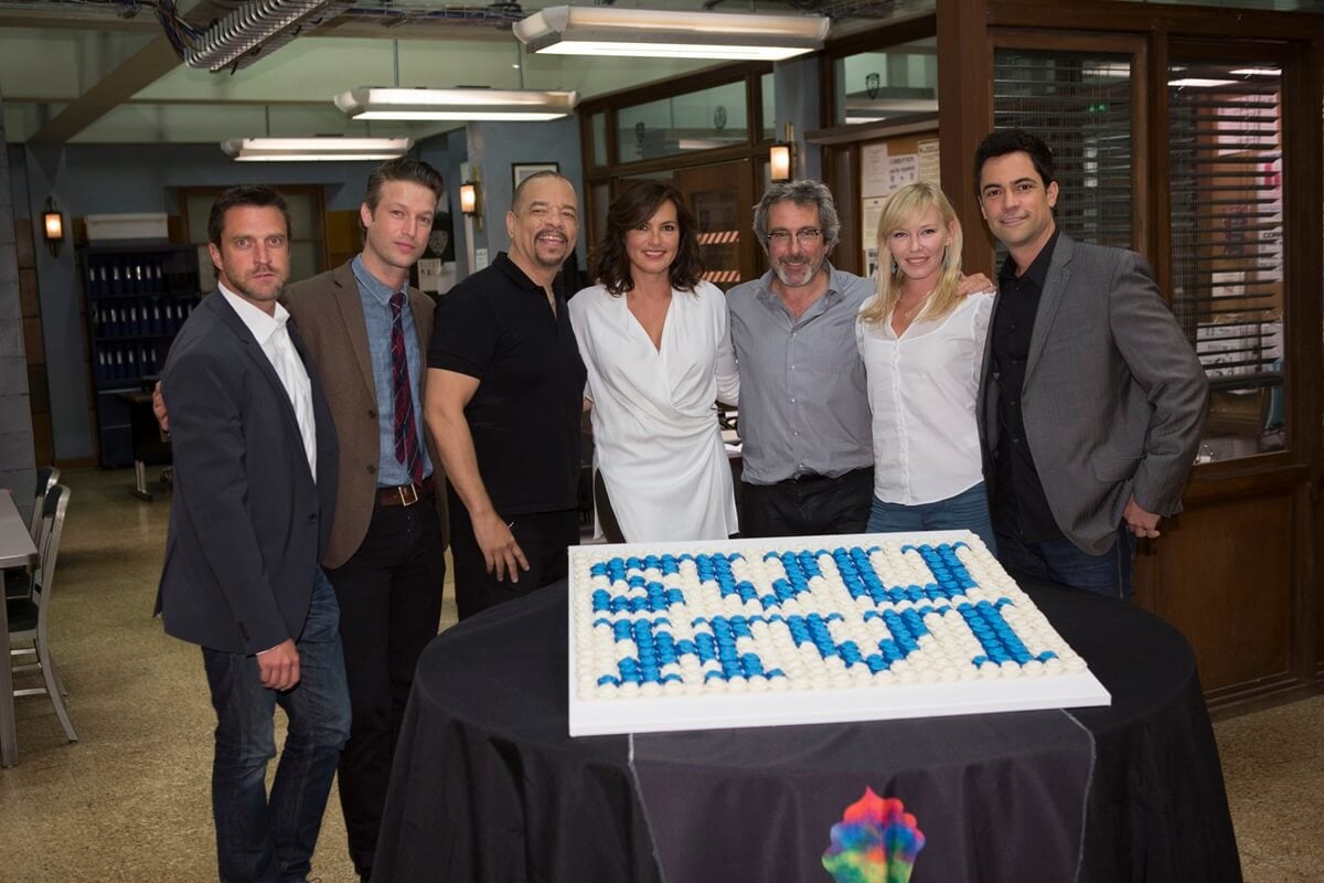 Warren Leight standing alongside his 'Law & Order' cast behind a cake.