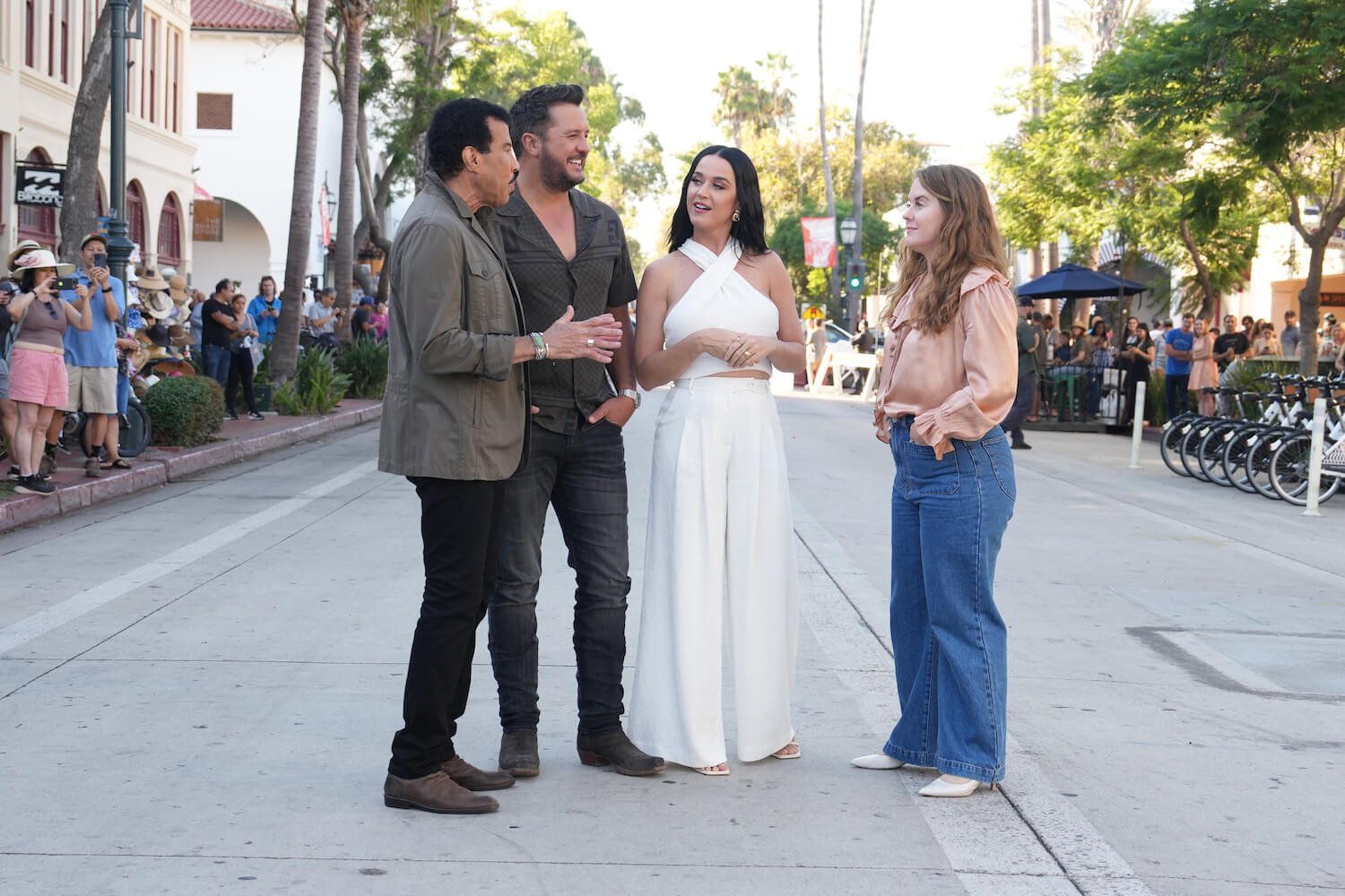 Lionel Richie, Luke Bryan, and Katy Perry speaking to a contestant outdoors