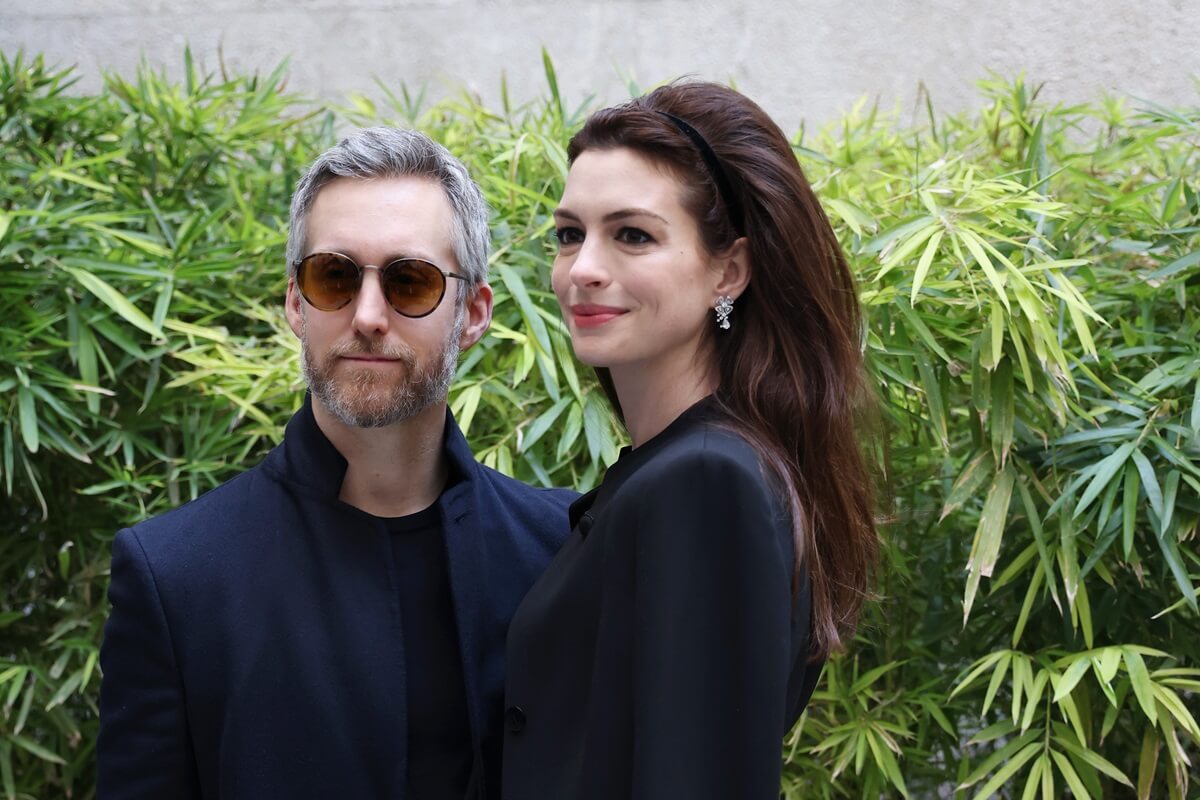 Anne Hathaway and husband Adam Shulman posing by plants.