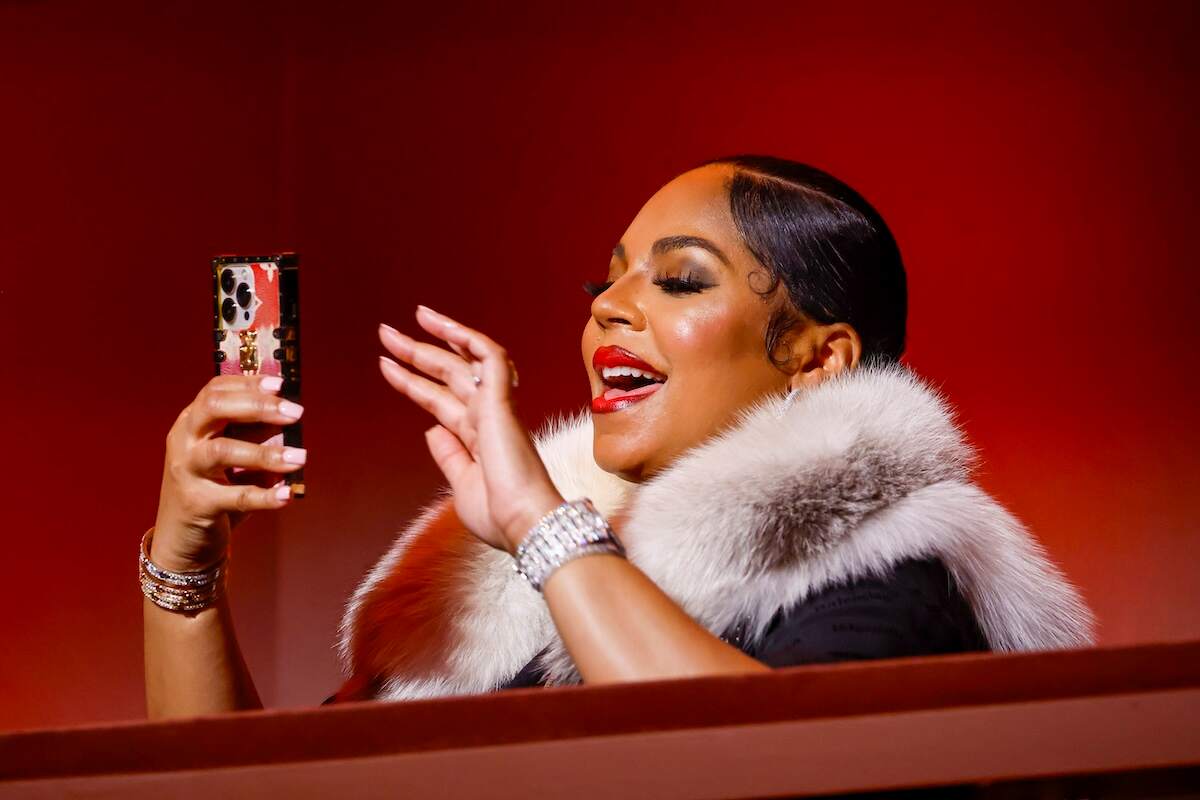 Wearing a fur coat, singer Ashanti snaps a photo with her iPhone during the 25th Annual Mark Twain Prize For American Humor