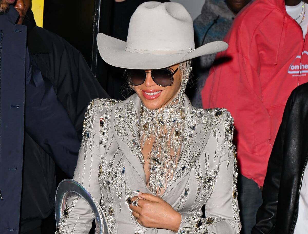 Beyoncé wears a silver jeweled dress, sunglasses, and a cowboy hat in the spirit of her new album, 'Cowboy Carter.'