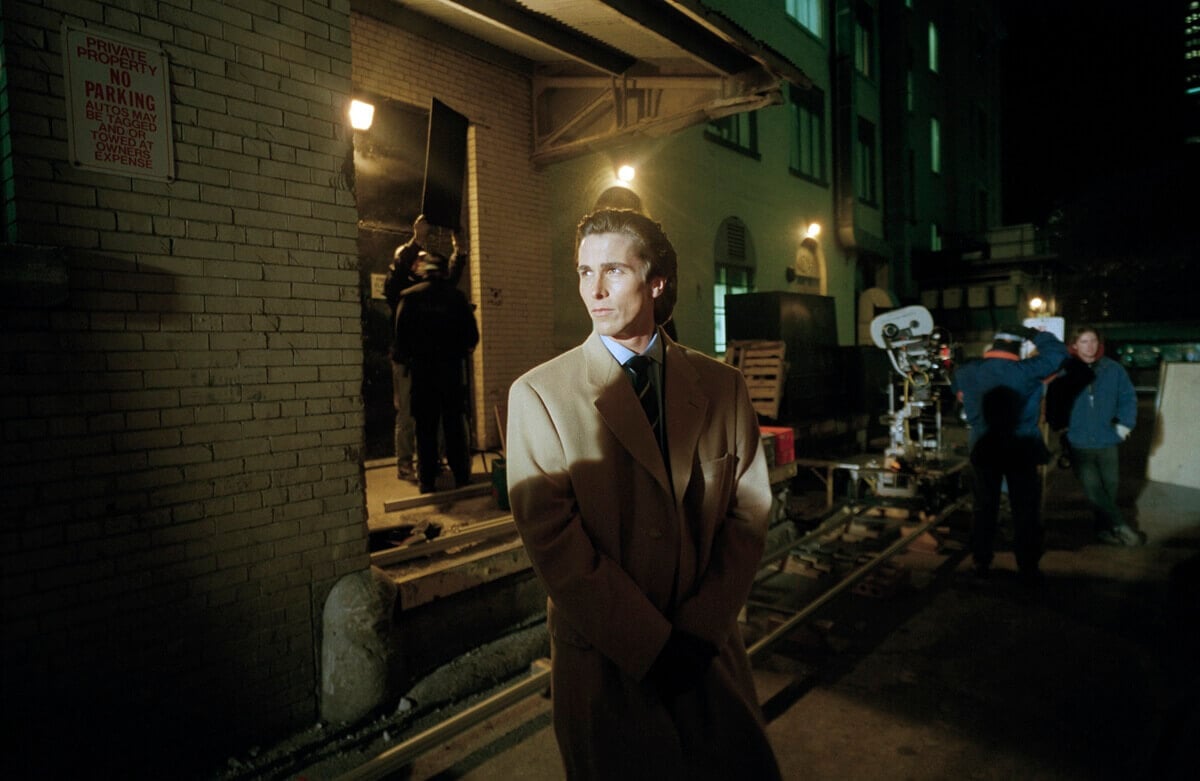 Christian Bale posing in a trench coat on the 'American Psycho' set.