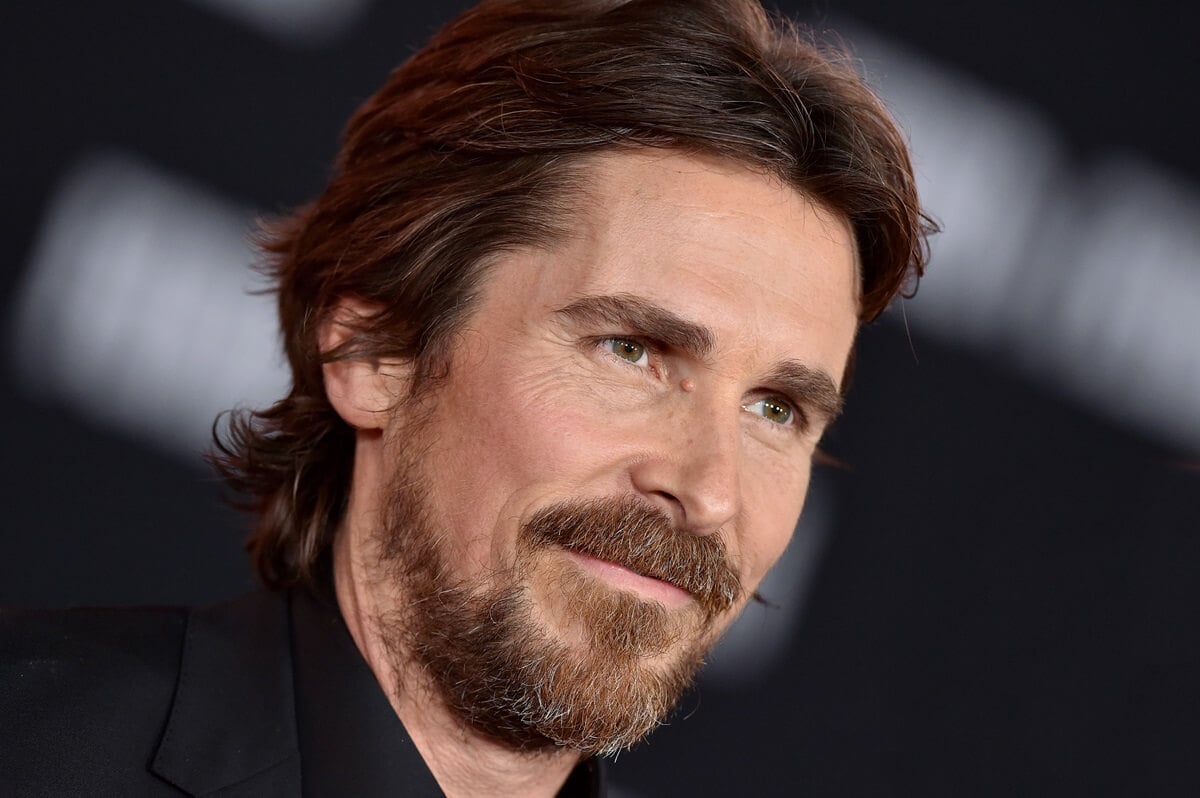 Christian Bale posing in a black suit at the premiere of "Ford v Ferrari".