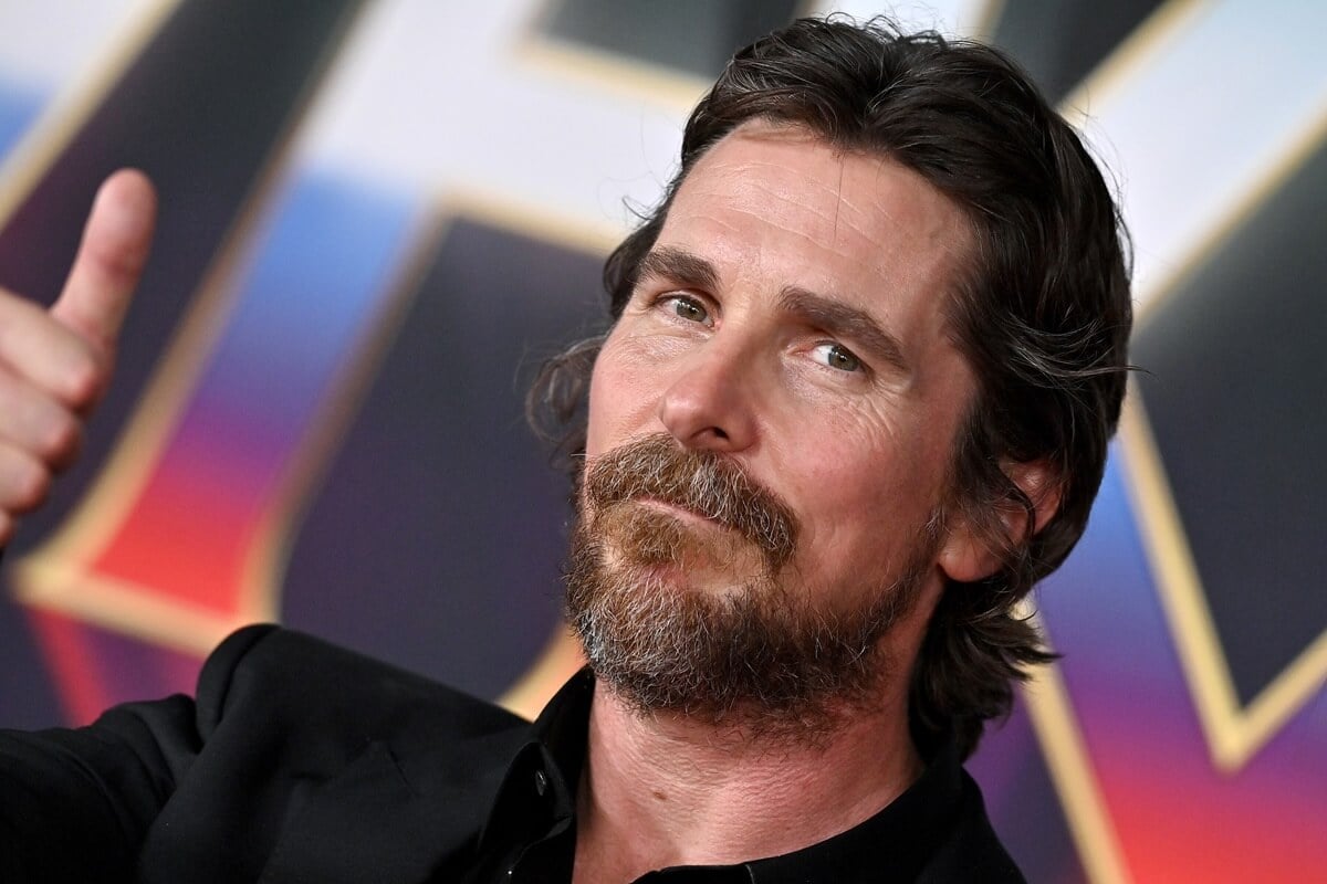 Christian Bale posing in a black suit at the premiere of 'Thor: Love and Thunder'.