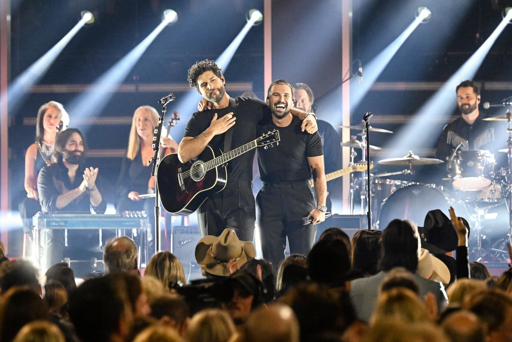 Dan Smyers and Shay Mooney of Dan + Shay on stage with their arms around each other in front of a crowd