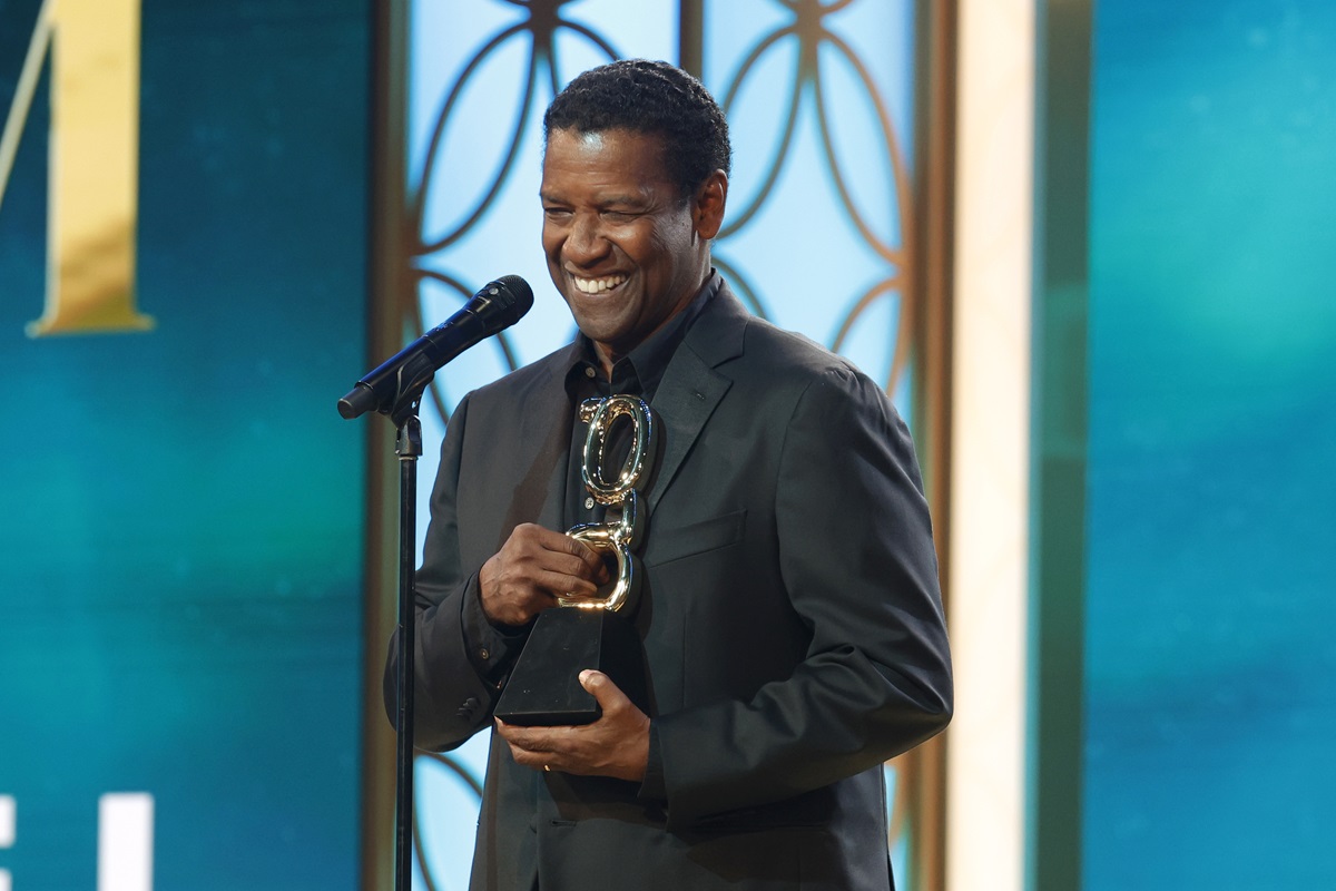 Denzel Washington the Film Icon Award onstage during the 2nd Annual theGrio Awards while wearing a black suit.