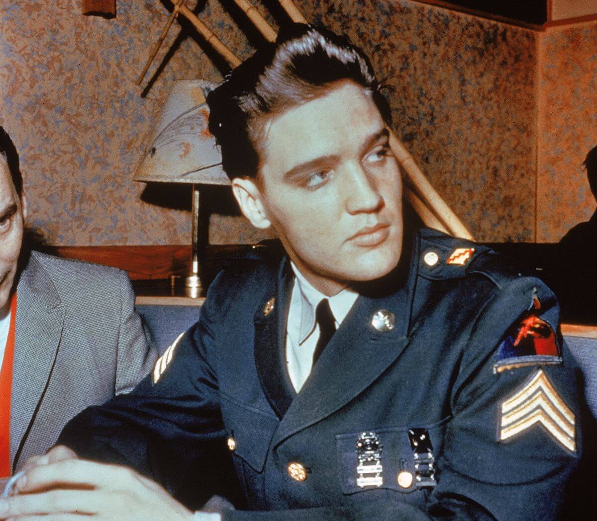 Elvis Presley wears his US Army uniform and sits in a booth.