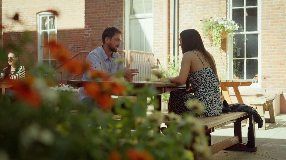 Farmer Brandon and Emerson sitting across from each other at an outdoor table in 'Farmer Wants a Wife' Season 2