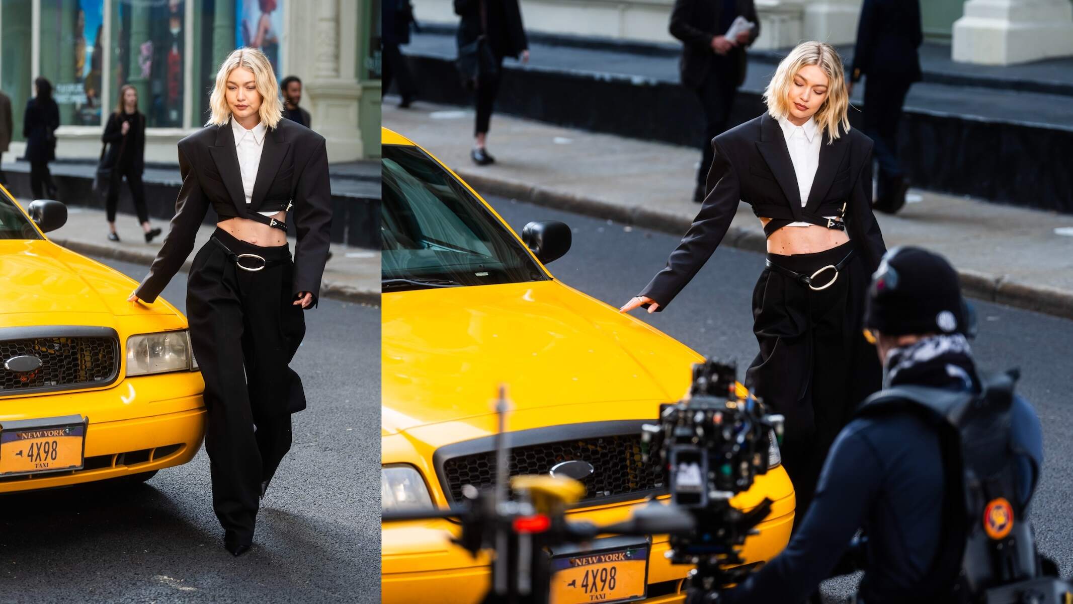 Model Gigi Hadid wears a black jacket and pants and walks by a taxi while filming a video for Maybelline on a NYC street