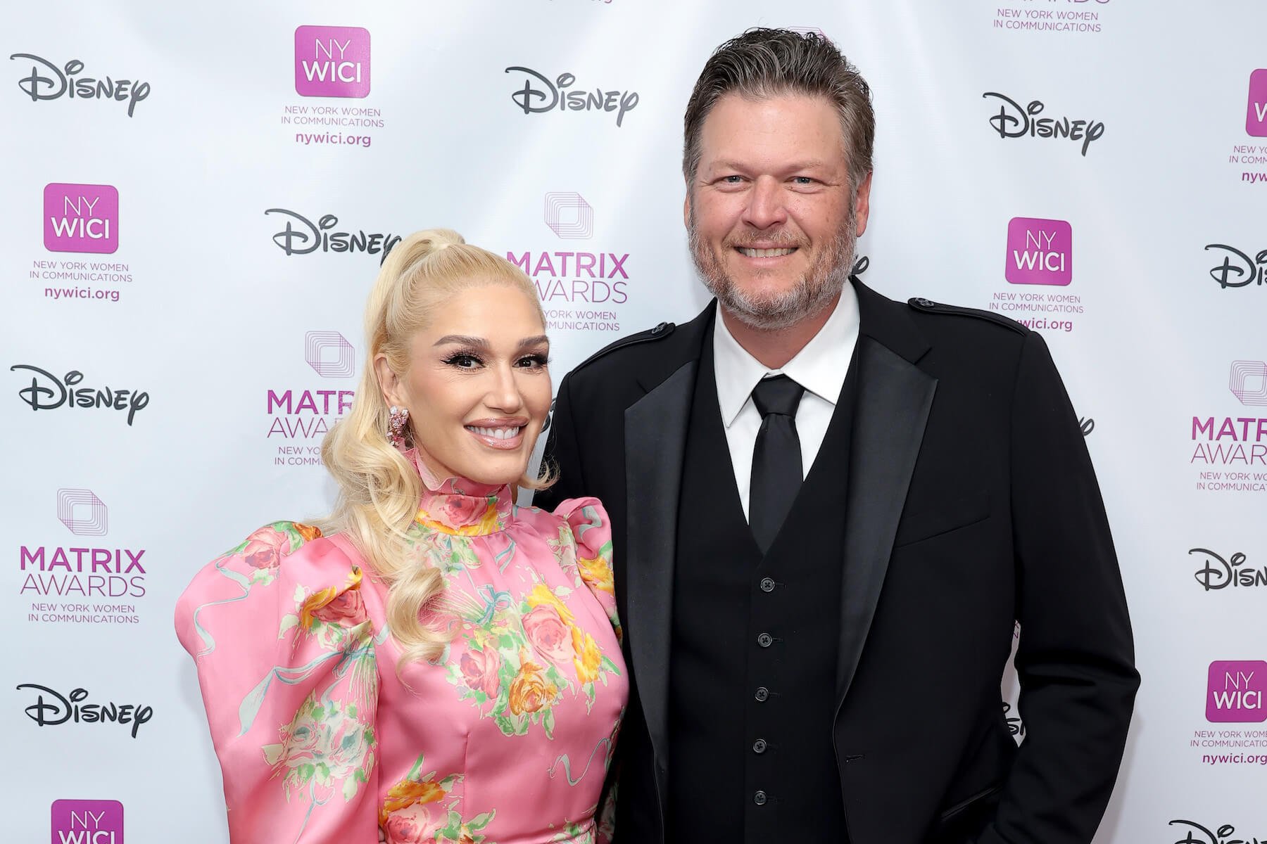 Gwen Stefani and Blake Shelton standing side by side and smiling at a Disney event