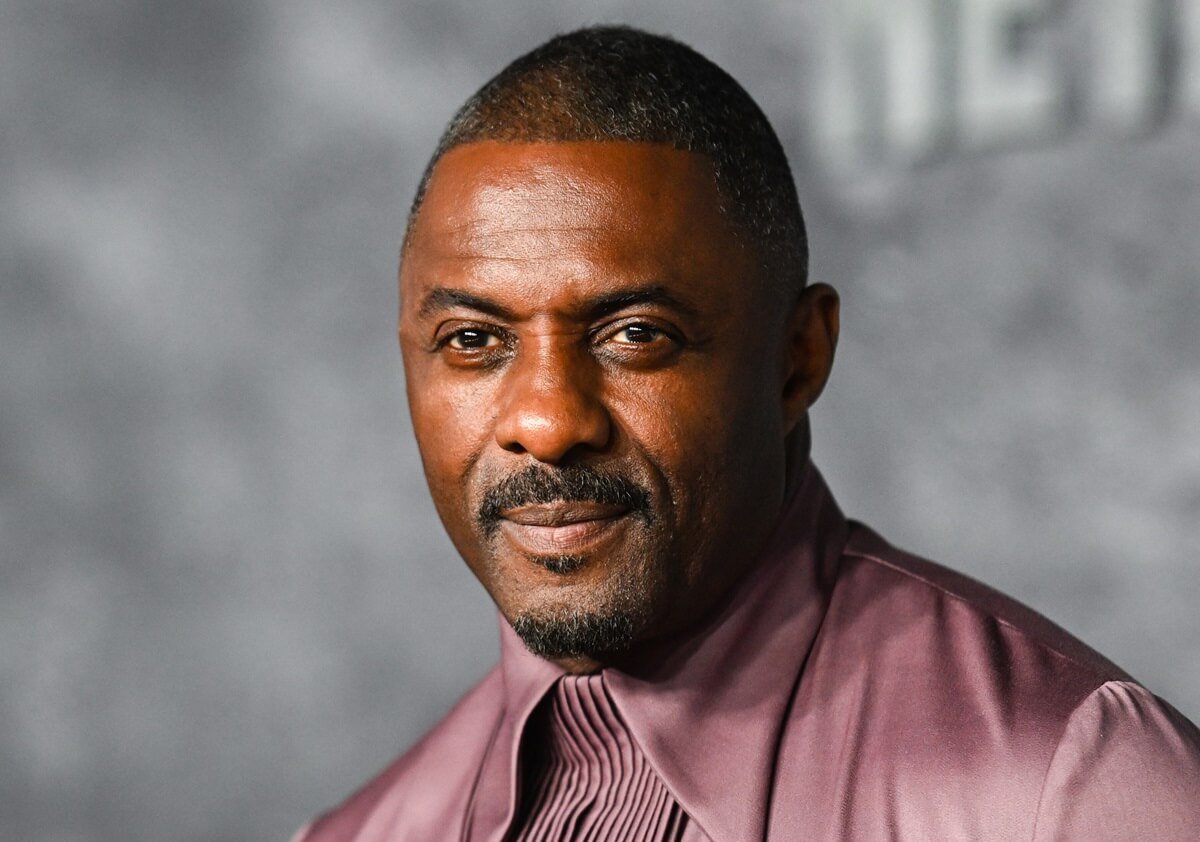 Idris Elba posing at the premiere of 'Luther: The Fallen Sun' while wearing a purple outfit.