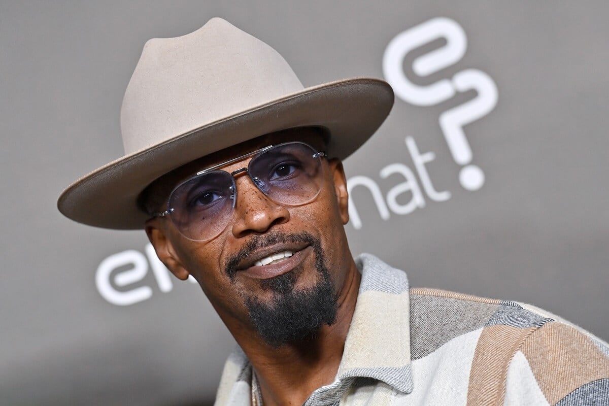 Jamie Foxx posing while wearing a white outfit and cowboy hat.