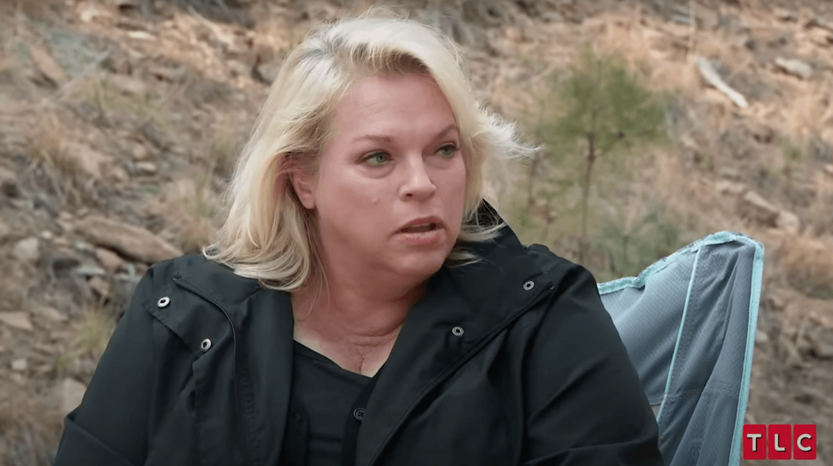 Janelle Brown sitting outside in a black jacket in 'Sister Wives'