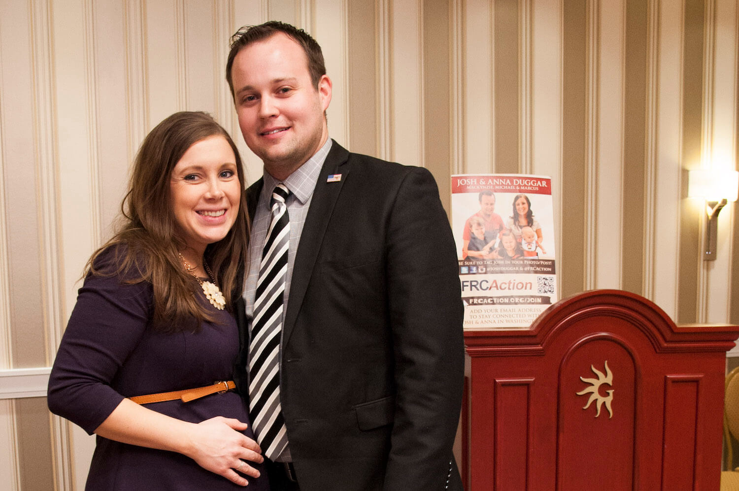 Josh and Anna Duggar embracing at a political event. Anna Duggar is pregnant and cradling her belly.