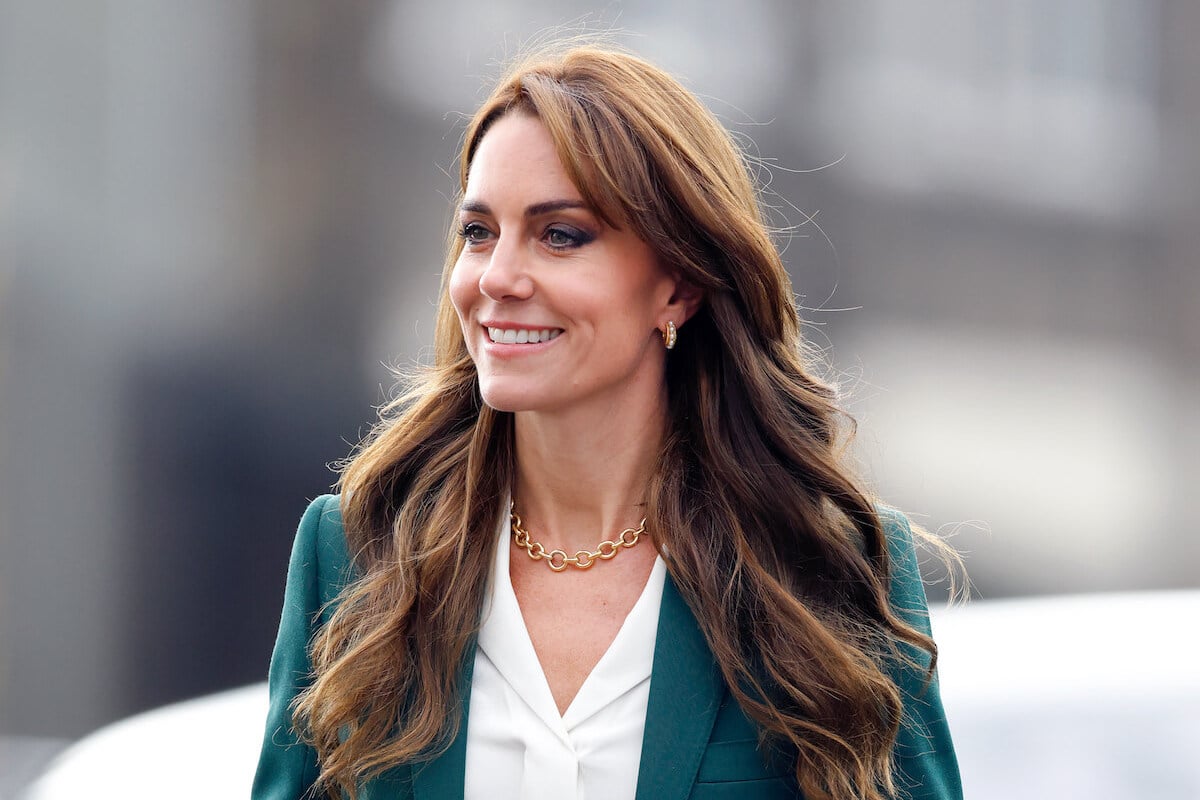 Kate Middleton, who was pictured in a paprazzi photo for the first time since surgery, looks on wearing a green blazer and white shirt.