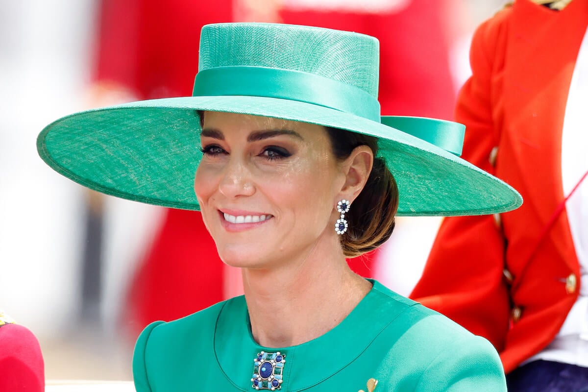 Kate Middleton, whose 'Celebrity Big Brother' contestant uncle Gary Goldsmith has spoken out about conspiracy theories, smiles and looks on wearing a green hat and suit