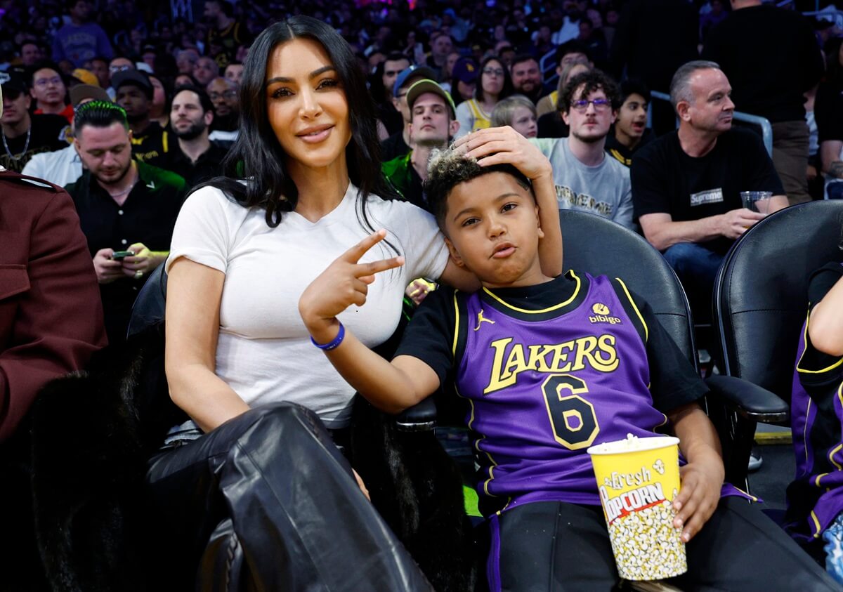 Kim Kardashian and her son Saint West sitting next to each other on the Basketball player.