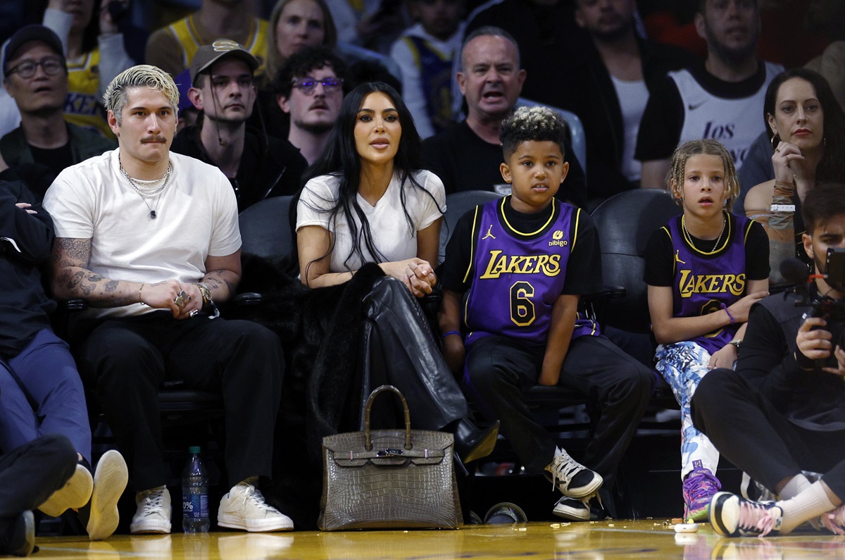 Kim Kardashian and her son Saint West sitting next to each other on the Basketball player.