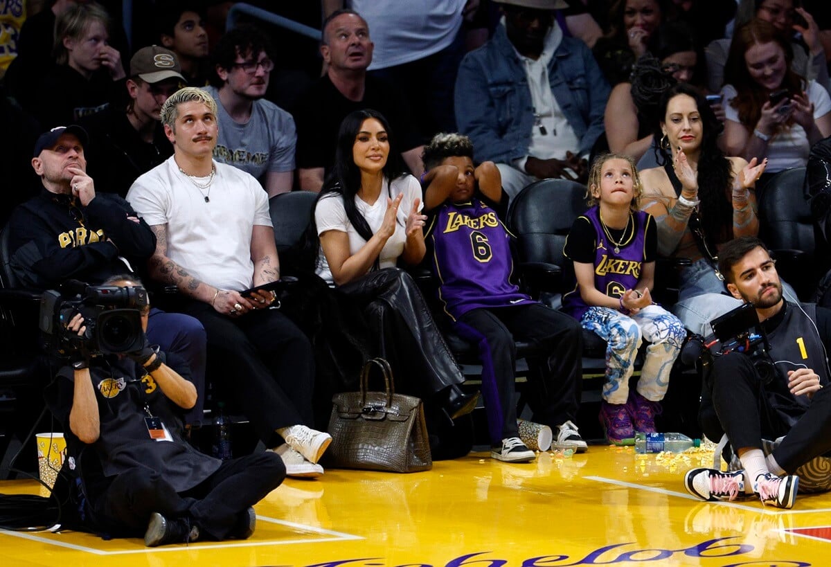 Kim Kardashian and her son Saint West sitting next to each other on the Basketball player.