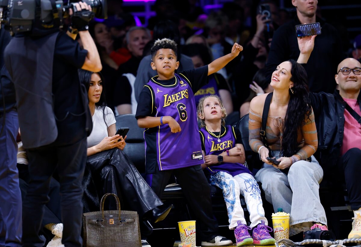 Kim Kardashian and her son Saint West sitting next to each other on the Basketball player.