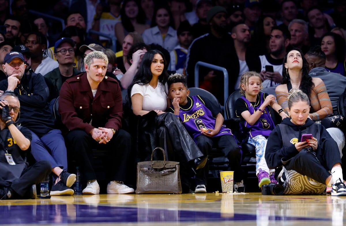 Kim Kardashian and her son Saint West sitting next to each other on the Basketball player.