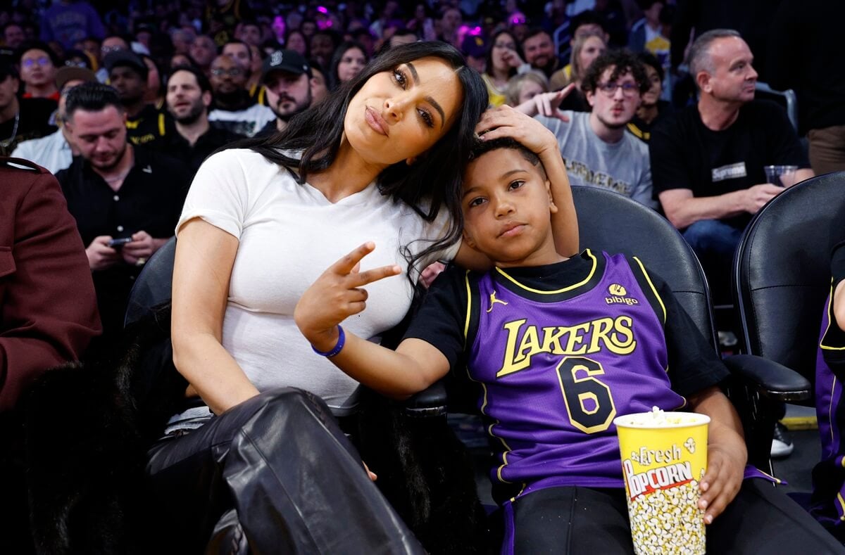 Kim Kardashian and her son Saint West sitting next to each other on the Basketball player.