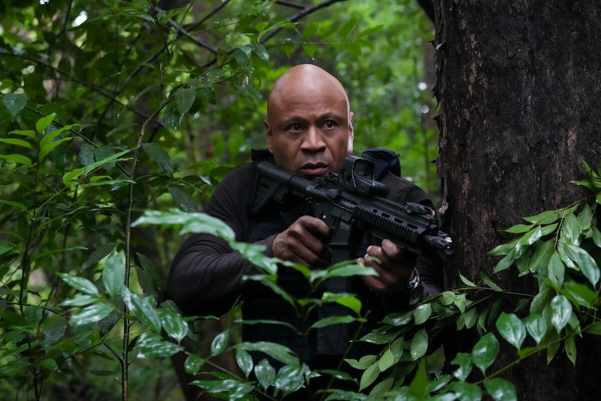 LL Cool J holding a gun and hiding in the trees in 'NCIS: Hawai'i'