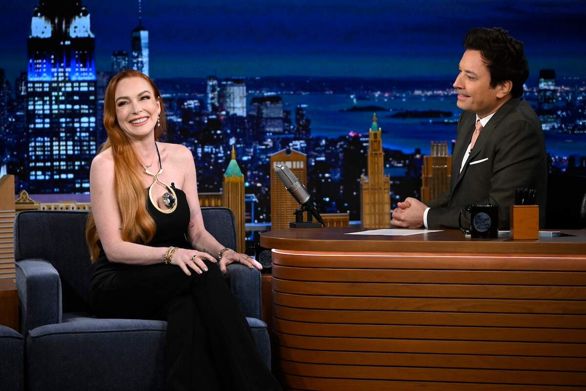 Actor Lindsay Lohan wears a black gown and laughs with Jimmy Fallon on his late night show