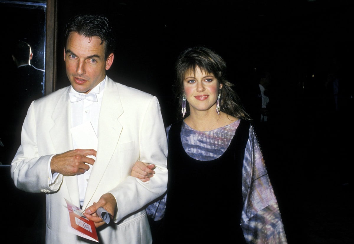 Mark Harmon wearing a white suit walking next to Pam Dawber.