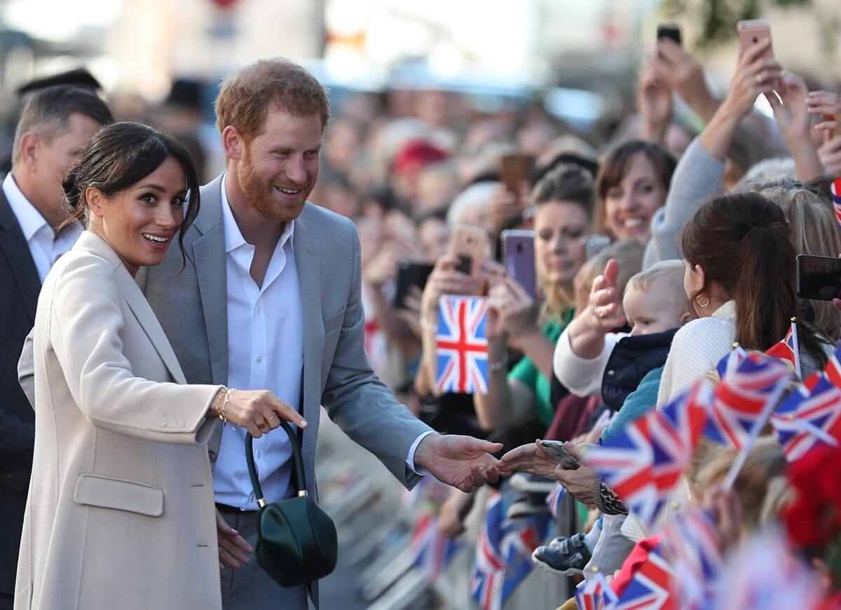 Meghan Markle and Prince Harry greet well-wishers as they arrive for an engagement at Edes House during an official visit to Sussex