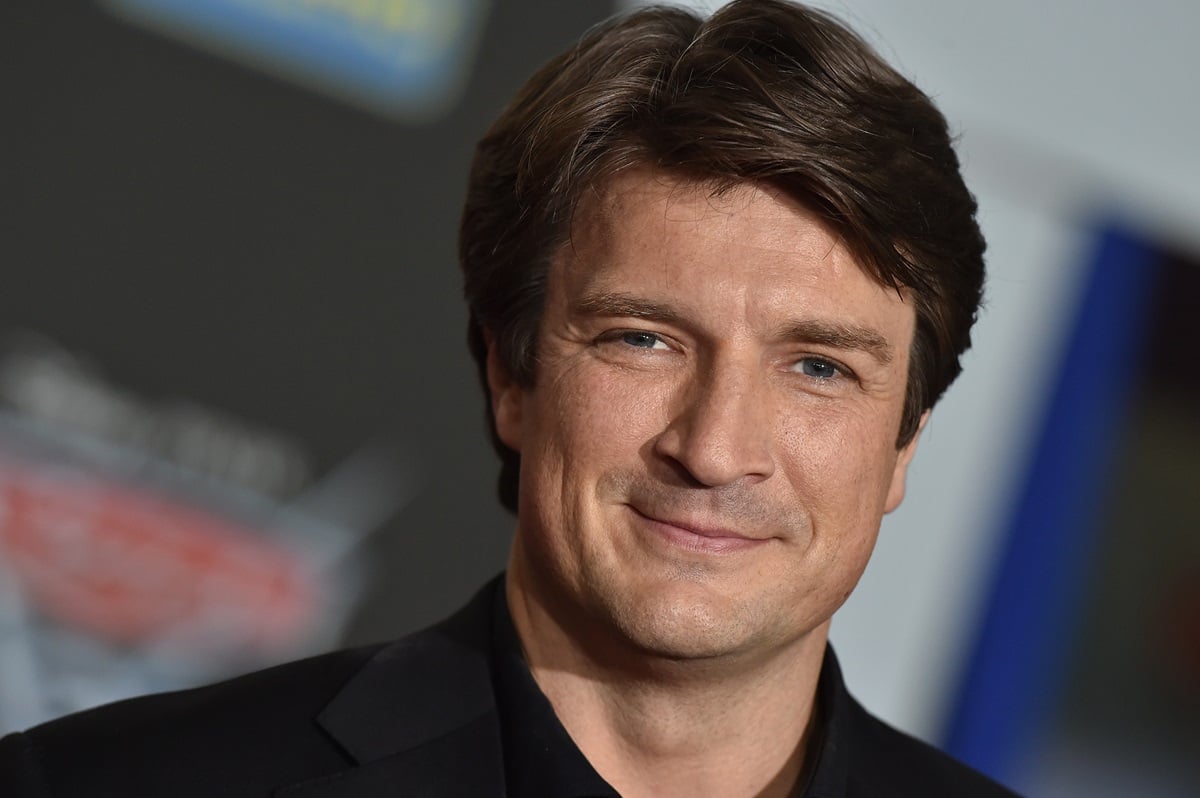 Nathan Fillion posing in a suit at the premiere of 'Cars'.