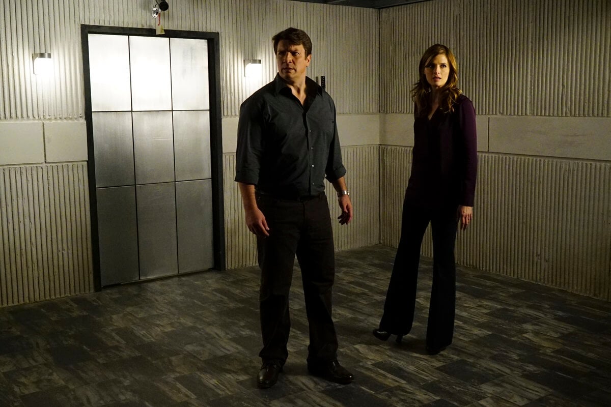 Nathan Fillion and Stana Katic standing next to each other on the set of 'Castle'.