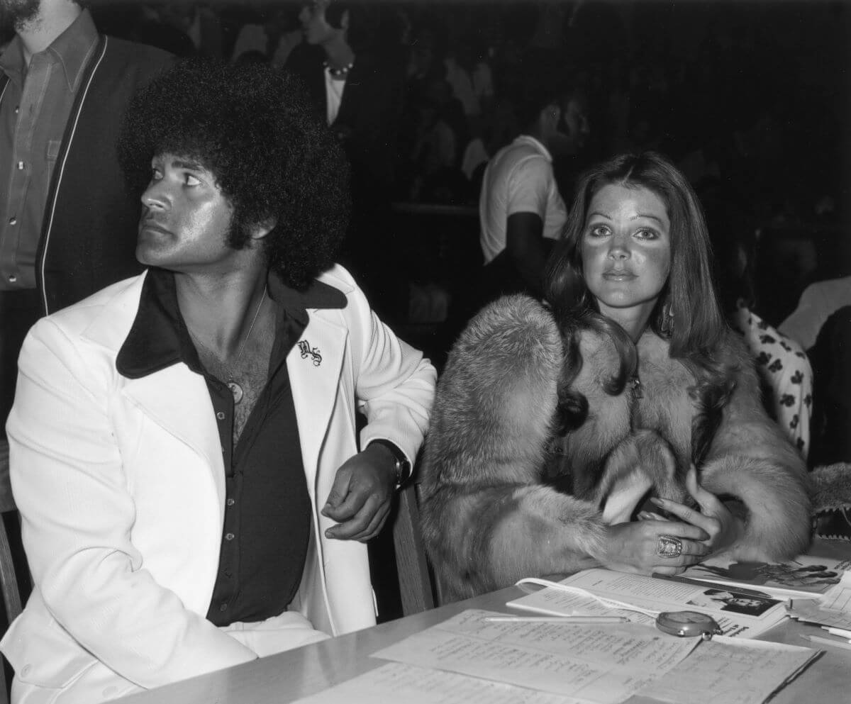 A black and white picture of Mike Stone and Priscilla Presley sitting at a table together.