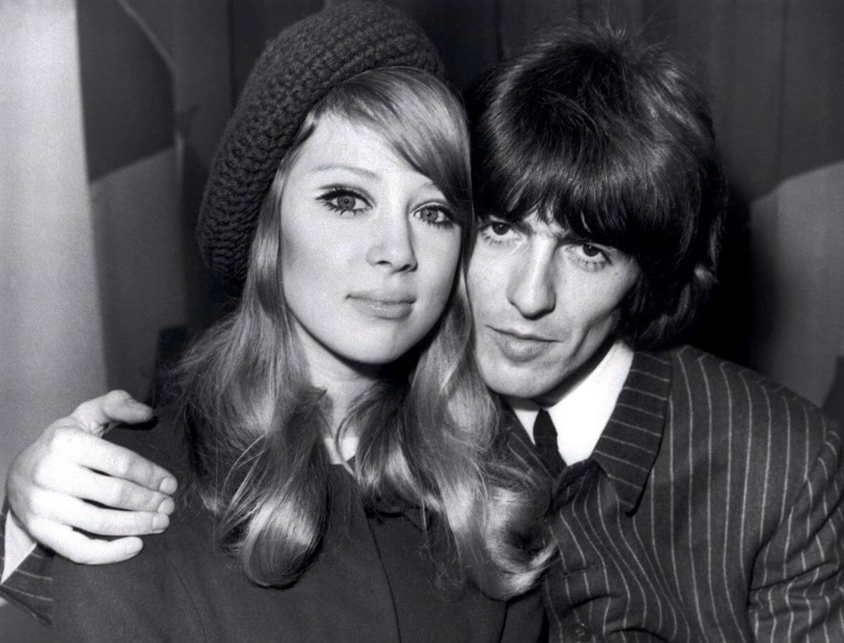 A black and white picture of George Harrison with his arm around Pattie Boyd's shoulders.