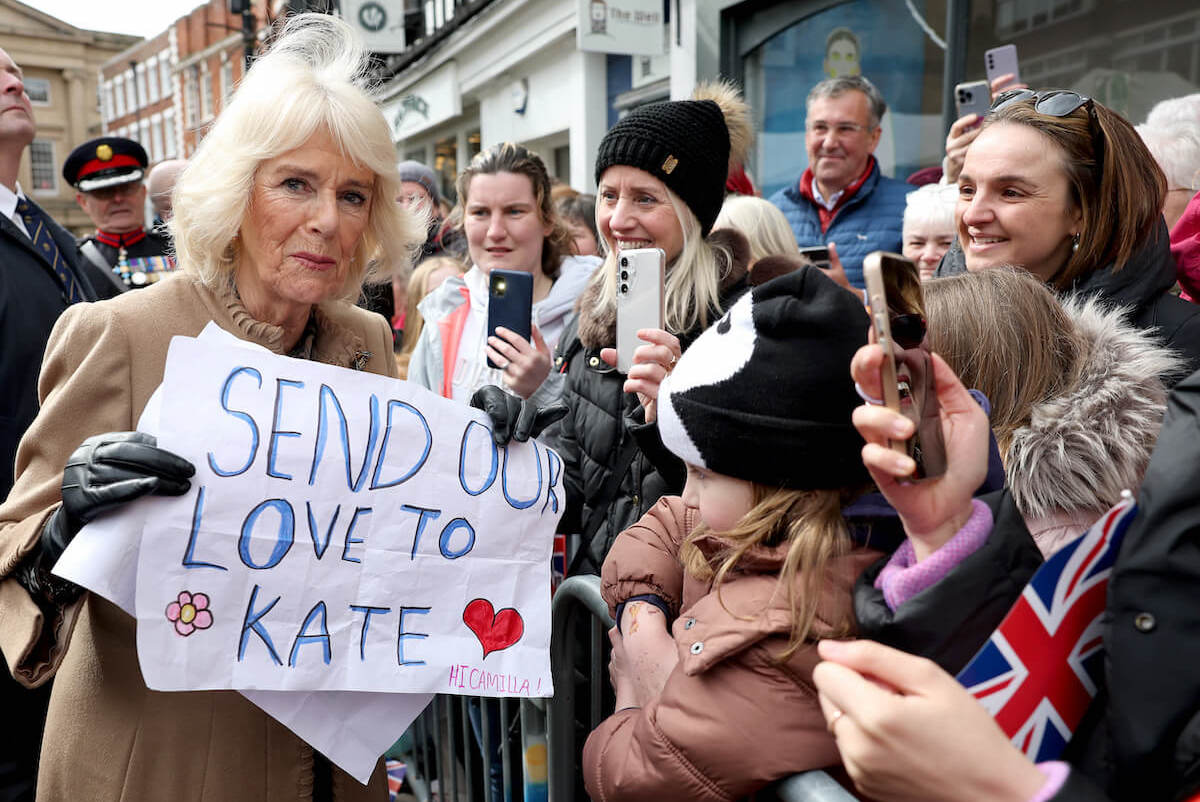 Queen Camilla, who is a 'pillar of strength' for Kate Middleton amid her cancer diagnosis, holds up a sign for Kate Middleton