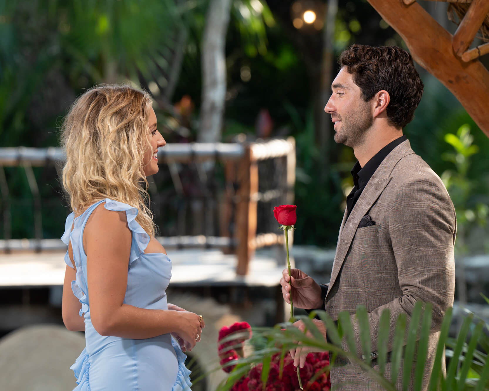 Daisy Kent looking at Joey Graziadei outdoors in 'The Bachelor' Season 28. Joey is about to hand Daisy a rose.
