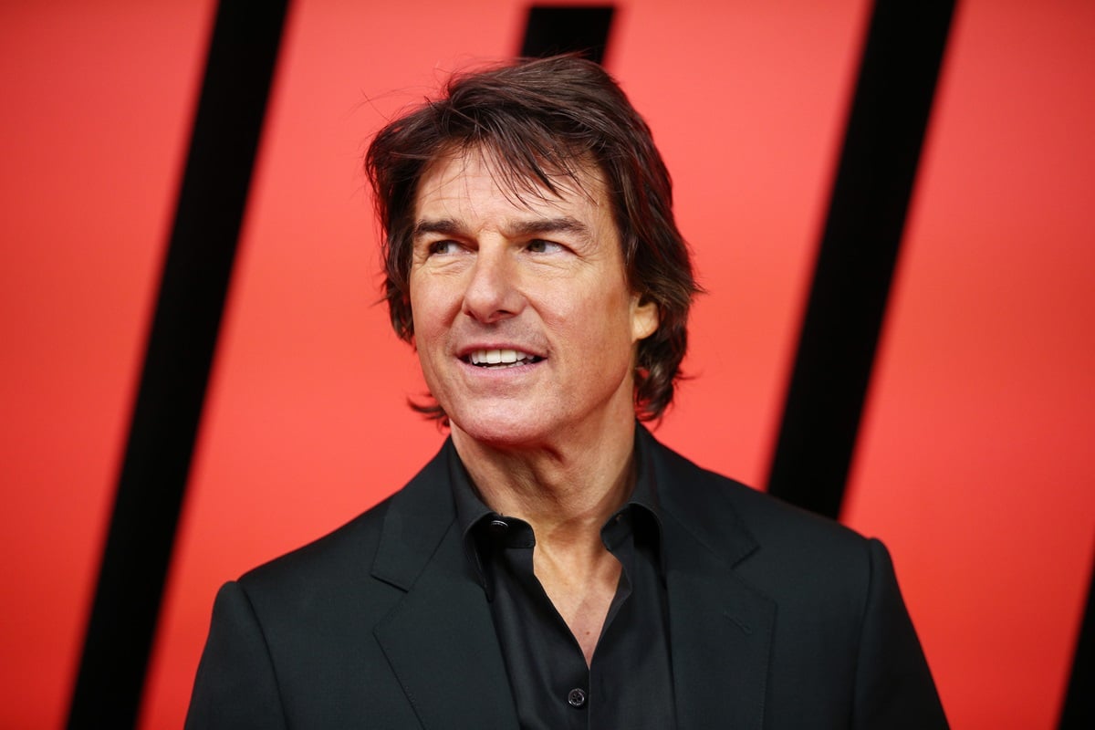 Tom Cruise posing while wearing a black suit.