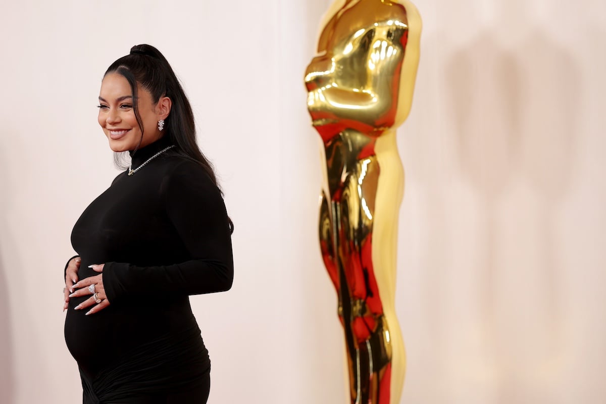 Pregnant Vanessa Hudgens standing next to a large Oscar statue